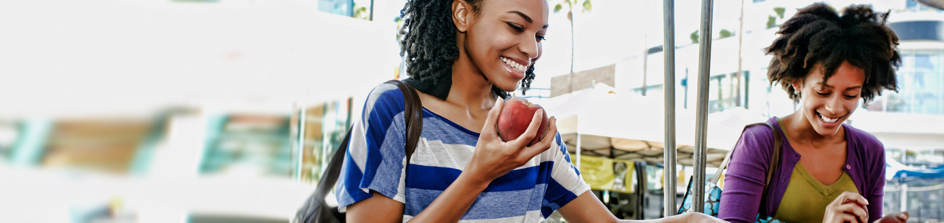 two women walking , one eating and apple