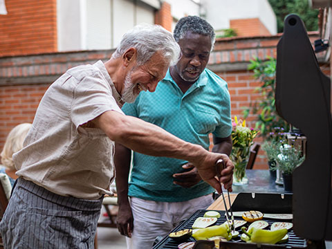 Two senior men preparing barbecue for vegan dinner with friends.